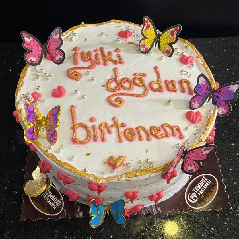 Renkli kelebekler ve altın kenarlı doğum günü pastası